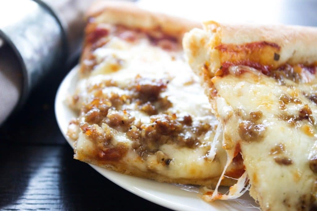 photo of two square slices of sheet pan pizza on white plate.