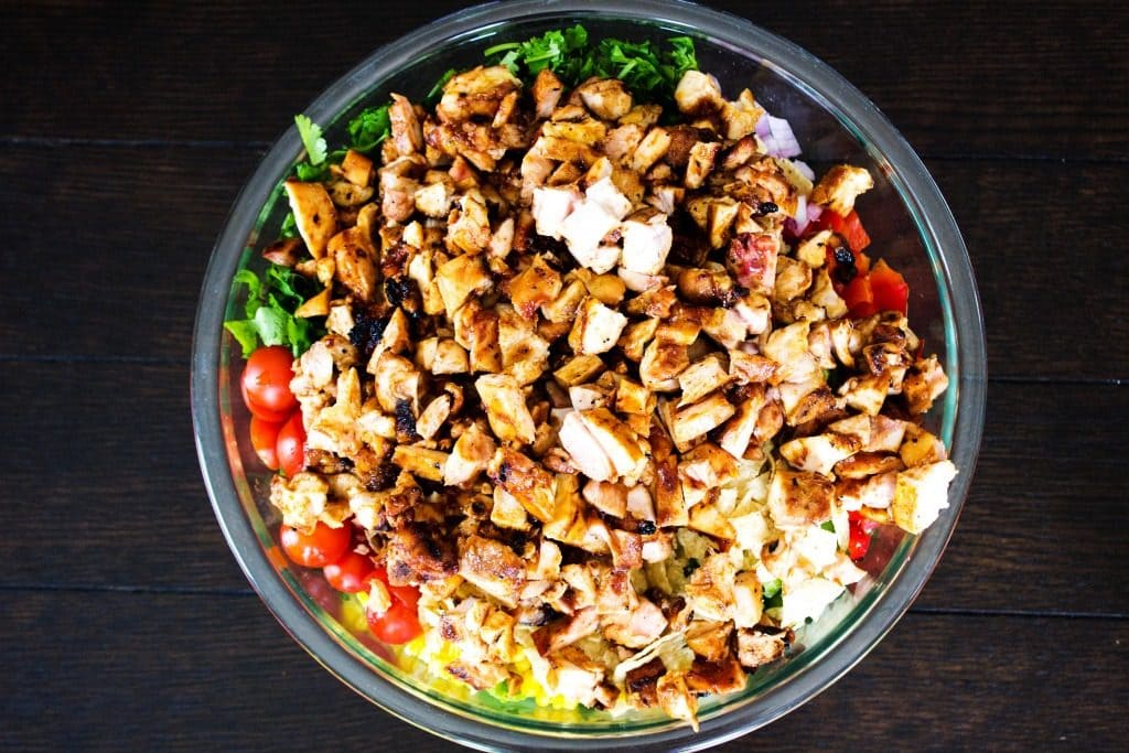 CREAMY BBQ RANCH CHICKEN SALAD is guaranteed to be a spring & summer favorite. Packed with BBQ chicken, taco chips, greens and veggies, and tossed with a homemade BBQ Ranch dressing, this salad will be a real crowd pleaser. CREAMY BBQ RANCH CHICKEN SALAD- Glass bowl, wooden table