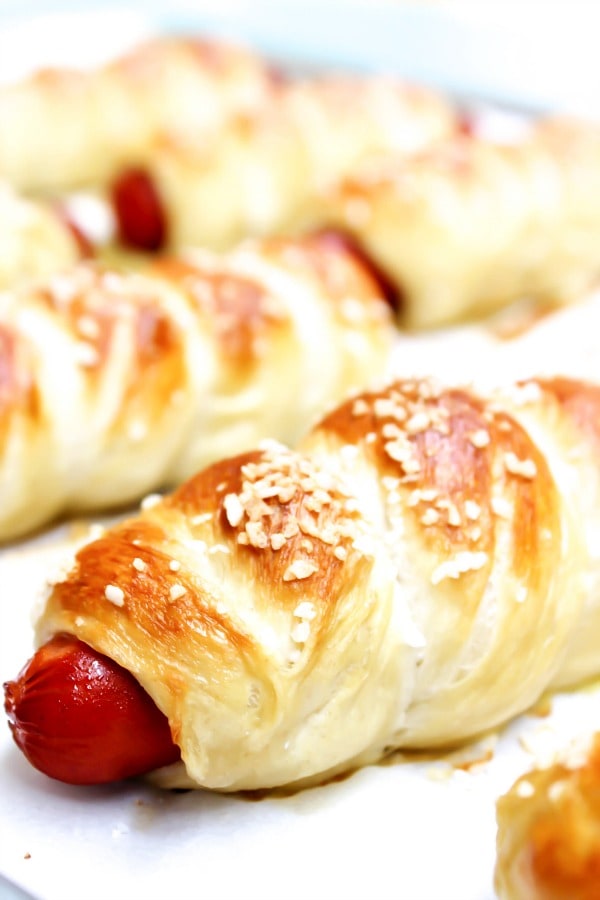 Simple & delicious these EASY PRETZEL HOT DOGS are the perfect combination a hot dog and a soft pretzel- a kid favorite in our home. close up photo of pretzel hot dog on a sheet pan