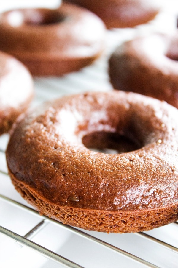 Triple Chocolate Baked Cake Donuts - a Devil's Food Cake Donut, glazed with a chocolate ganache and topped off with mini-chocolate chips. TRIPLE CHOCOLATE BAKED CAKE DONUTS RECIPE - unfrosted donut on cooling rack