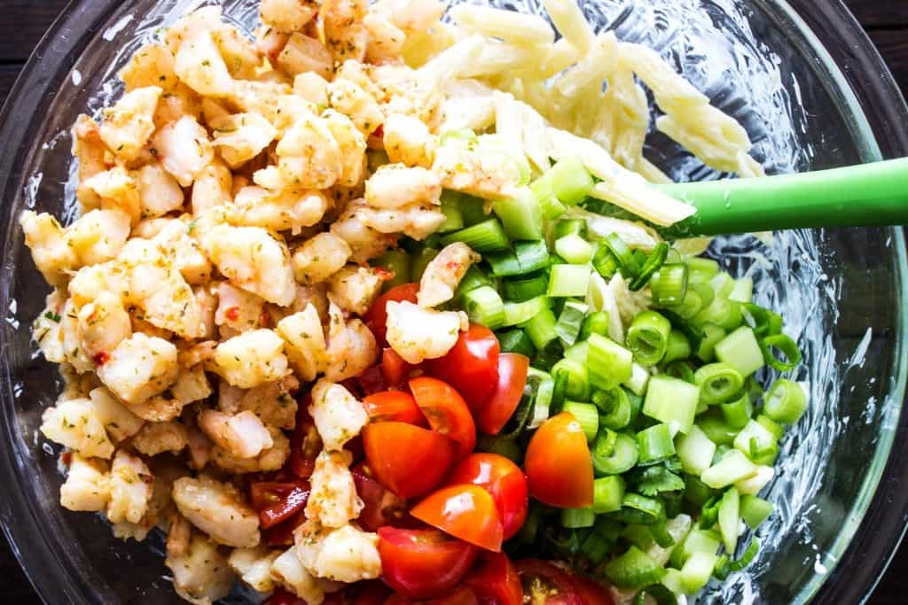 SHRIMP SCAMPI PASTA SALAD a classic summer dish with an added twist. With just a few simple ingredients, this pasta salad is elevated to a whole new level of deliciousness. SHRIMP SCAMPI PASTA SALAD Ingredients in class bowl on wooden table