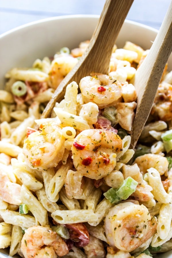 SHRIMP SCAMPI PASTA SALAD a classic summer dish with an added twist. With just a few simple ingredients, this pasta salad is elevated to a whole new level of deliciousness. SHRIMP SCAMPI PASTA SALADWooden spoons, off-white bowl
