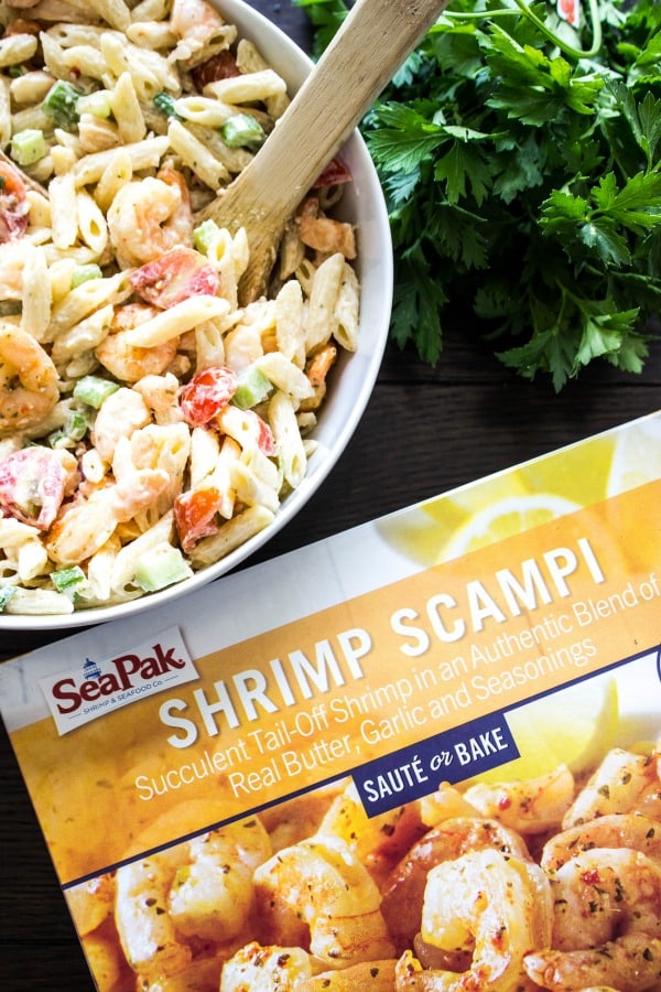 SHRIMP SCAMPI PASTA SALAD a classic summer dish with an added twist. With just a few simple ingredients, this pasta salad is elevated to a whole new level of deliciousness. SHRIMP SCAMPI PASTA SALAD off-white bowl, wooden table, fresh herbs