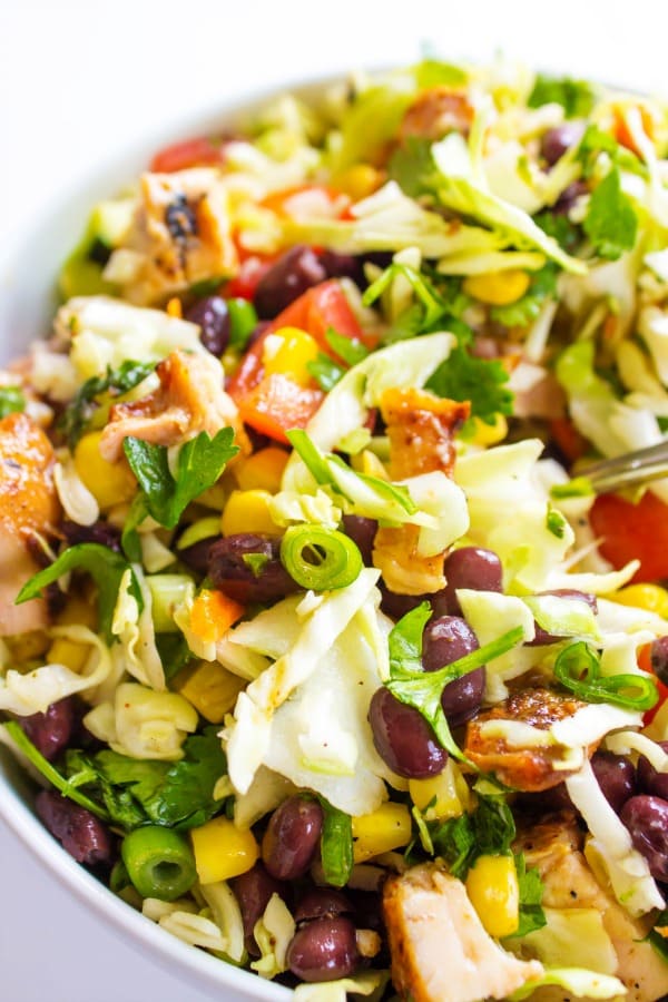 CHOPPED SOUTHWESTERN SALAD shredded green cabbage, black beans, corn, green onion, tomatoes, cilantro, taco strips {if desired} and the best cilantro lime dressing. Full of flavor and easy to prepare in less than 20 minutes; get ready to devour my favorite summer salad. CHOPPED SOUTHWESTERN SALAD White bowl, white table
