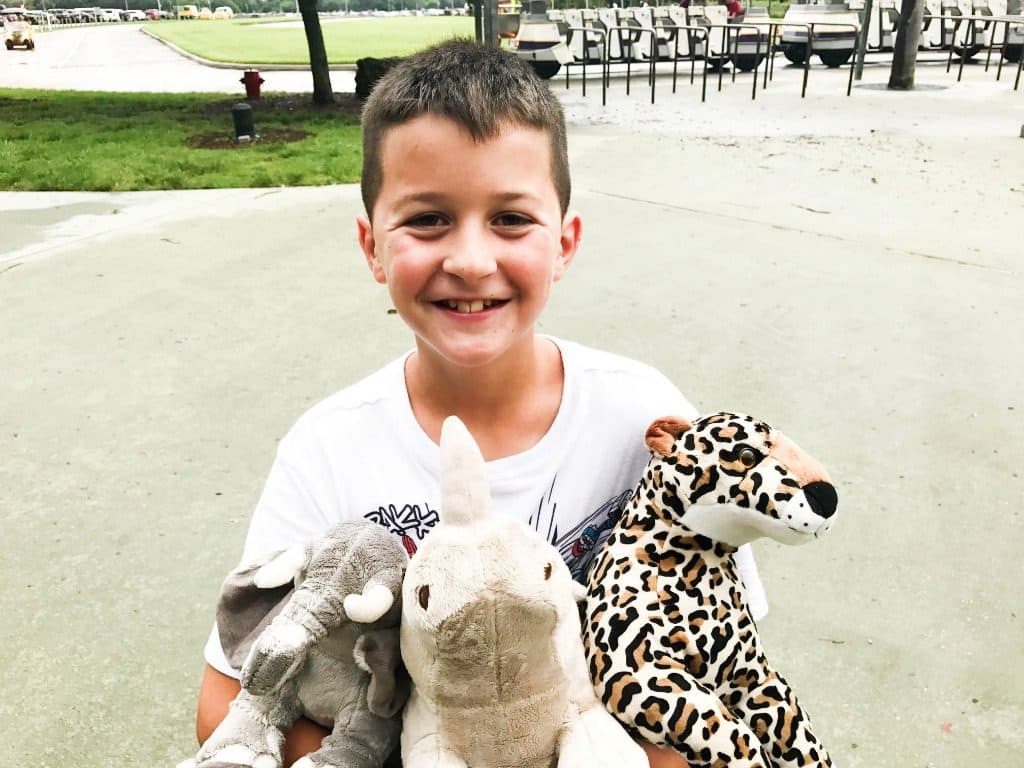 Photo of a young boy, Madden, holding stuffed animals and smiling