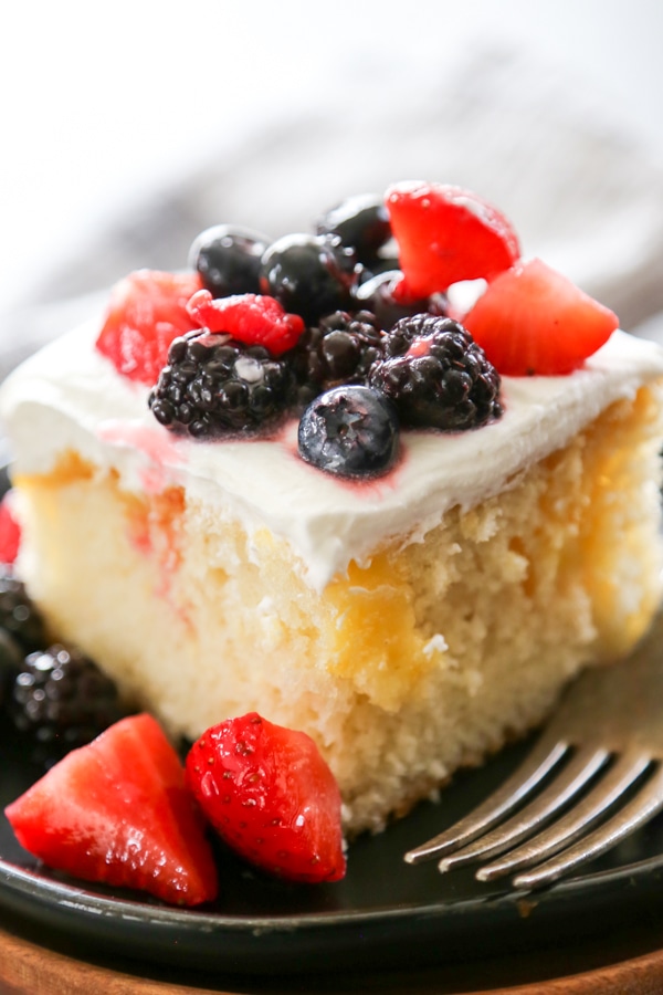 a slice of lemon poke cake topped with berries.