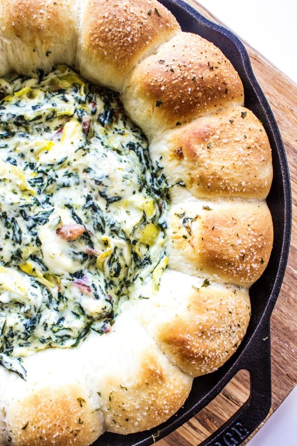 SPINACH ARTICHOKE BACON DIP RECIPE- creamy, delicious and easy to prepare this is a party must have. Adding bacon to your classic spinach artichoke dip is a fantastic twist that all your friends & family love. SPINACH ARTICHOKE BACON DIP RECIPE- Wooden cutting board and metal skillet