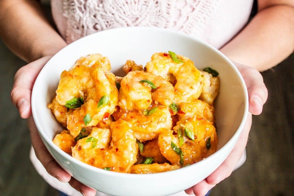 Photo of girl holding bowl of firecracker shrimp