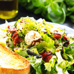 caprese chopped salad on plate with side of bread and balsamic drizzle