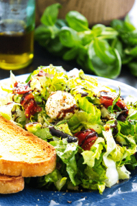 caprese chopped salad on plate with side of bread and balsamic drizzle