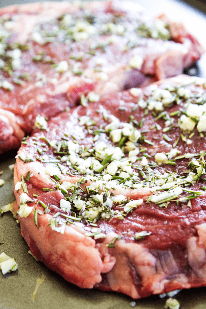 Raw Steak with Rosemary and Garlic Butter spread on top