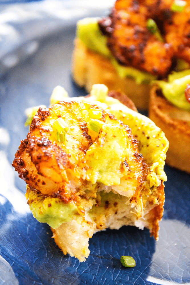 Simple, easy and insanely delicious, this recipe for CHILI RUBBED SHRIMP AND AVOCADO CROSTINI makes a great appetizer, snack or meal for busy nights. Chili Rubbed Shrimp and Avocado Crostini with bite taken out
