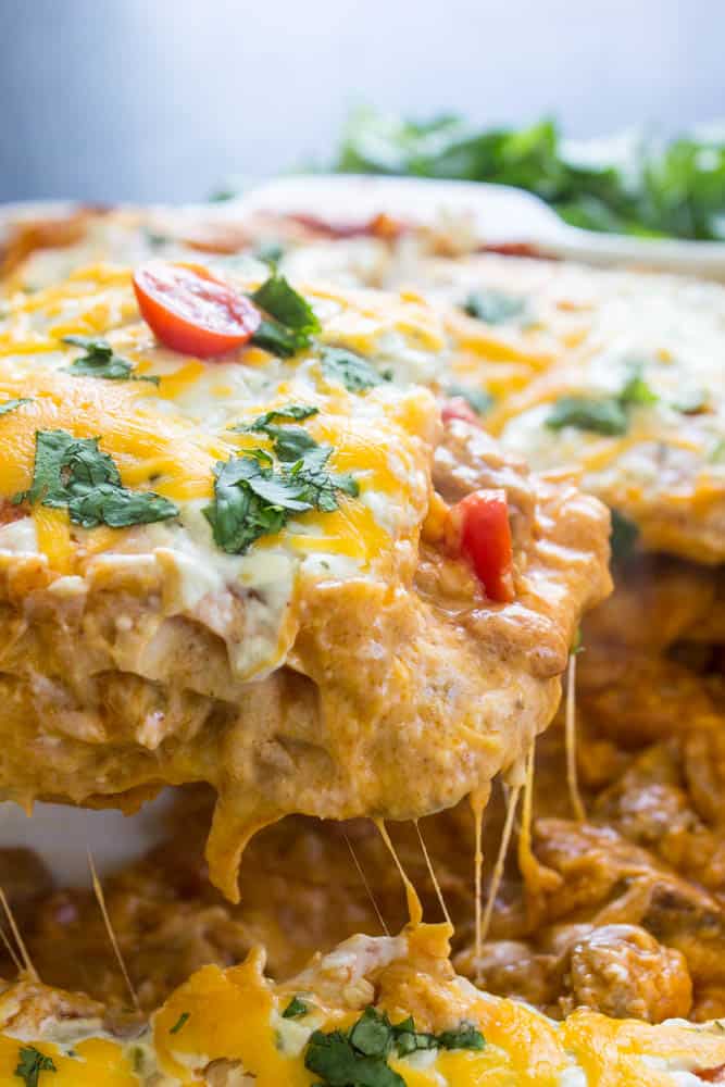 Steak and Queso Enchilada Casserole in baking tray with a serving being removed with a serving spoon