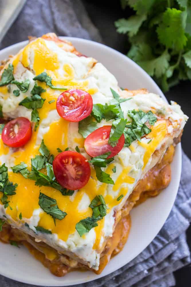 overhead photo of Steak and Queso Enchilada Casserole garnished with cilantro and cut cherry tomatoes