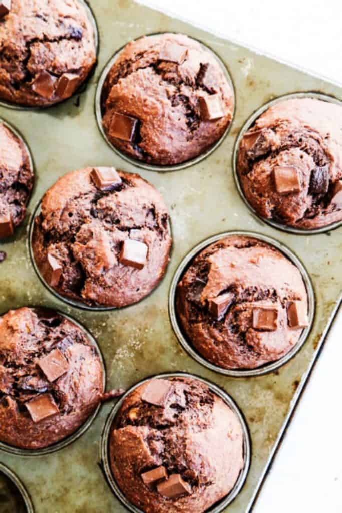 overhead shot chocolate muffins in muffin pan with chocolate chunks