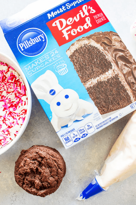 EASY WHOOPIE PIE RECIPE- Soft and chewy Devil's Food cake cookies sandwiched with cream cheese frosting, these whoopie pies are out of this world. pillsbury devil's food cake mix box next to bowl of sprinkles, stack of chocolate cookies, and a piping bag full of frosting