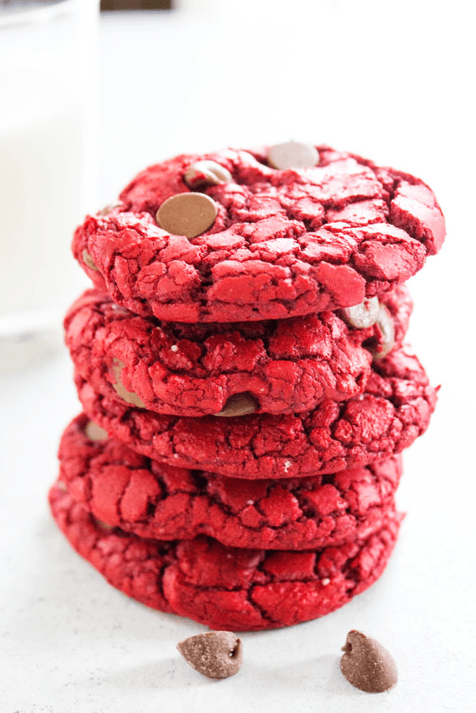 5 red velvet cookies in a stack with chocolate chips on counter