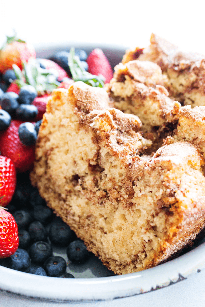 CINNAMON SUGAR BREAD is like eating a cinnamon & sugar cake donut but better. Easy & delicious this bread is ready to devour in an hour. photo of slices of cinnamon sugar bread on a plate with fresh strawberries and blueberries