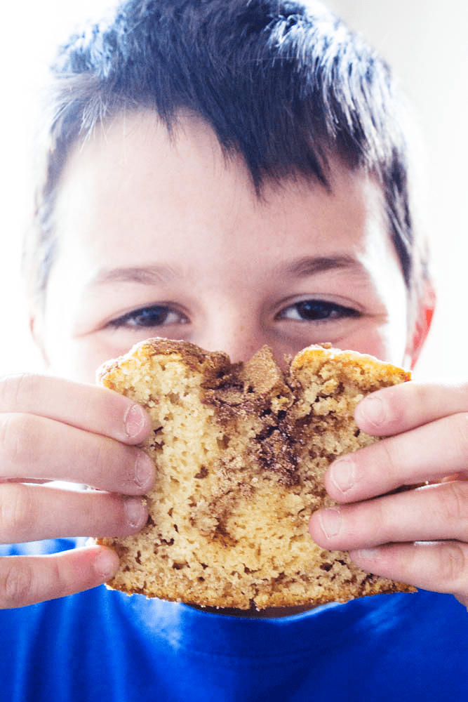 CINNAMON SUGAR BREAD is like eating a cinnamon & sugar cake donut but better. Easy & delicious this bread is ready to devour in an hour. photo of boy holding slice of cinnamon sugar bread up to his face
