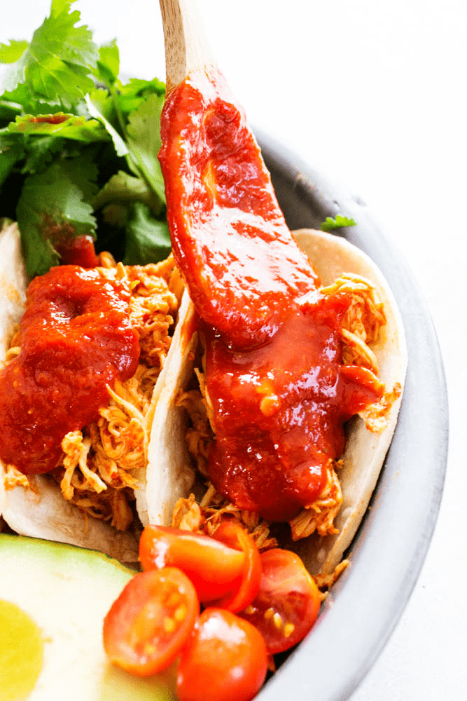 slow cooker chicken, chile colorado sauce, cilantro tacos, tomatoes, avocado, metal plate, spoon