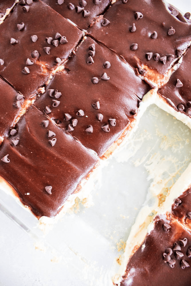 No-Bake Boston Cream Pie Cheesecake in glass baking pan with 2 squares removed