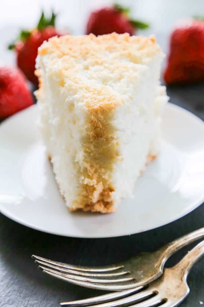 Angel Food Cake slice on plate with forks and strawberries whole in background
