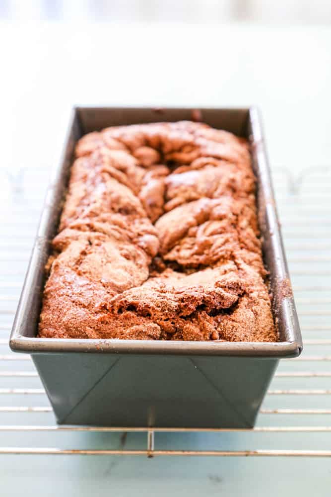 Chocolate Cinnamon Bread baked in metal bread pan on a wire rack