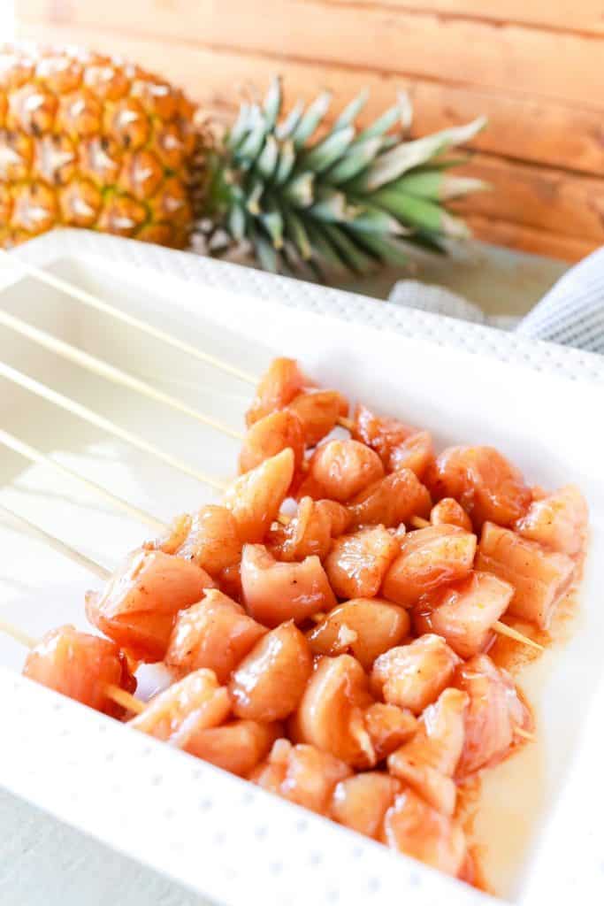raw marinated chicken on kabob skewers in a dish