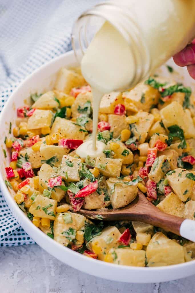 1. Tangy Southwest Dressing being poured from mason jar onto potato salad