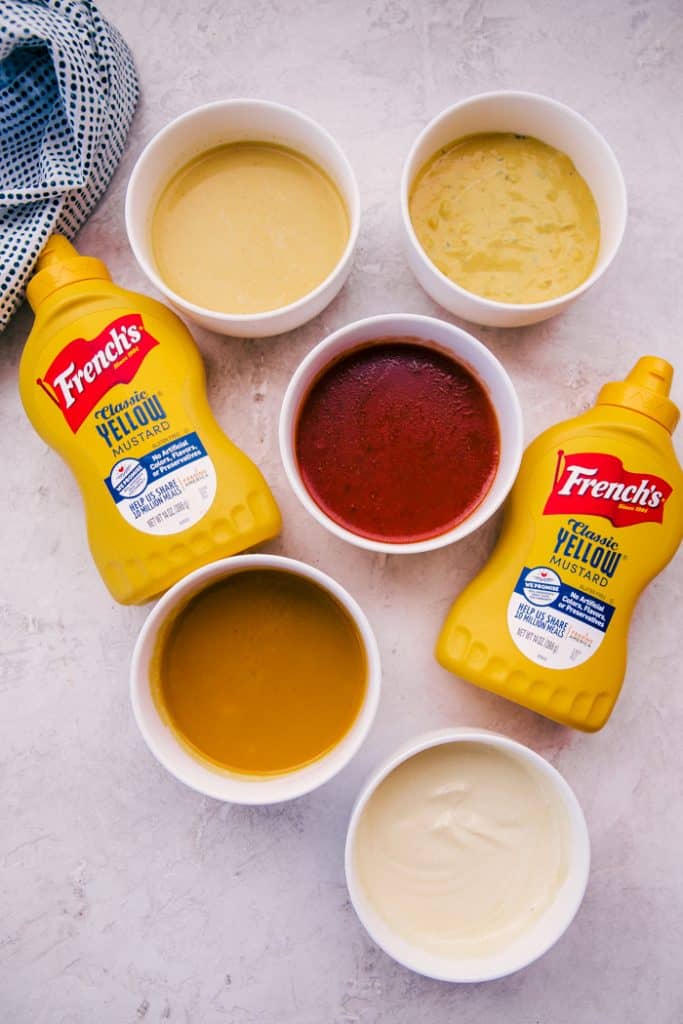5 easy dressings in white bowls next to 2 bottles of french's yellow mustard