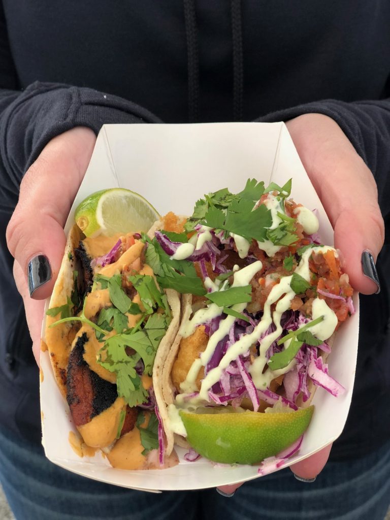 Paper tray with two street tacos, topped with cilantro and lime slices