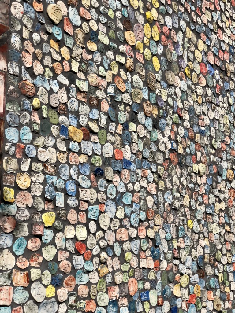 wall with little papers with faces drawn on them