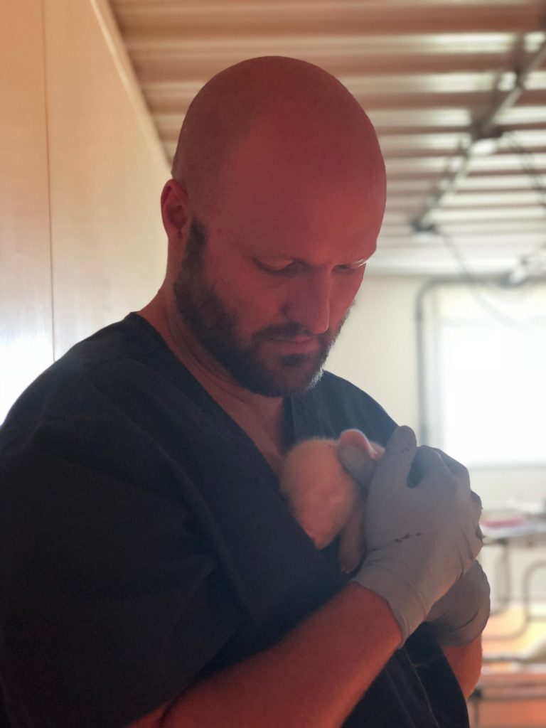 photo of Jake holding a piglet to his chest