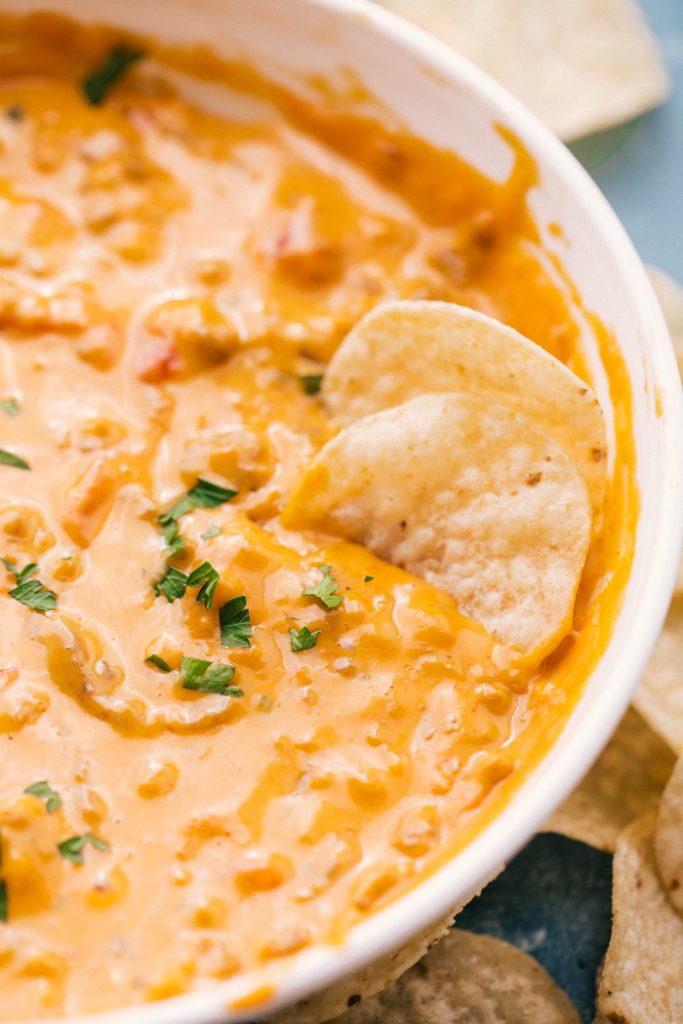 queso dip in white bowl with chips