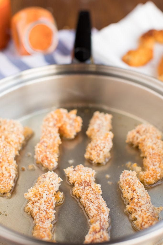 photo of a pork tenderloin fries frying in oil in a metal skillet