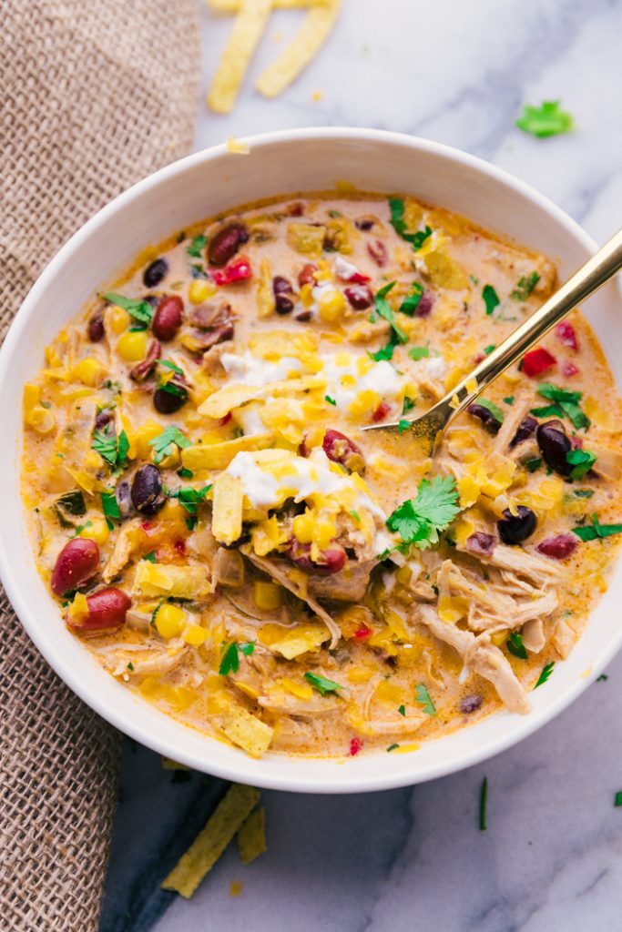 photo of a bowl of chicken tortilla soup with a spoon and garnishes