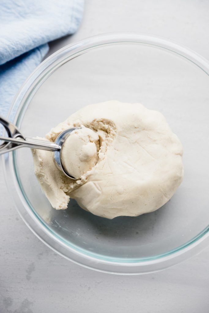 photo showing tortilla dough in a glass bowl with a dough scoop