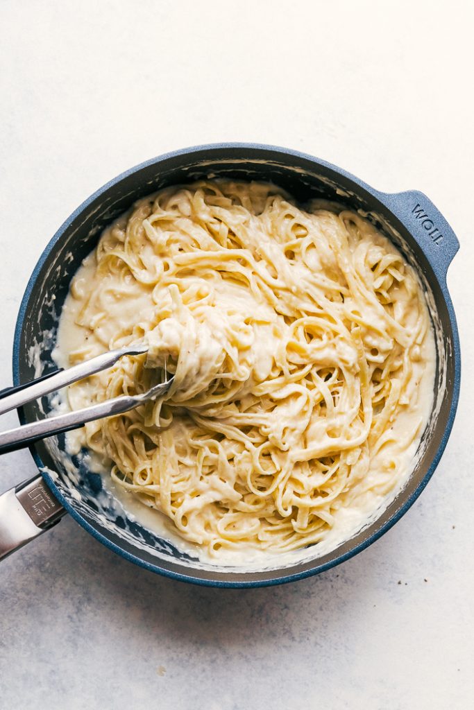 alfredo sauce in pan with noodles