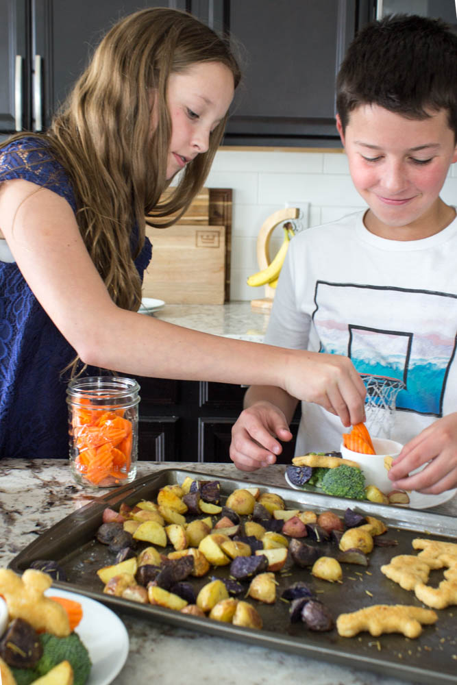 photo of 2 kids building a plate of food from the sheet pan dinner