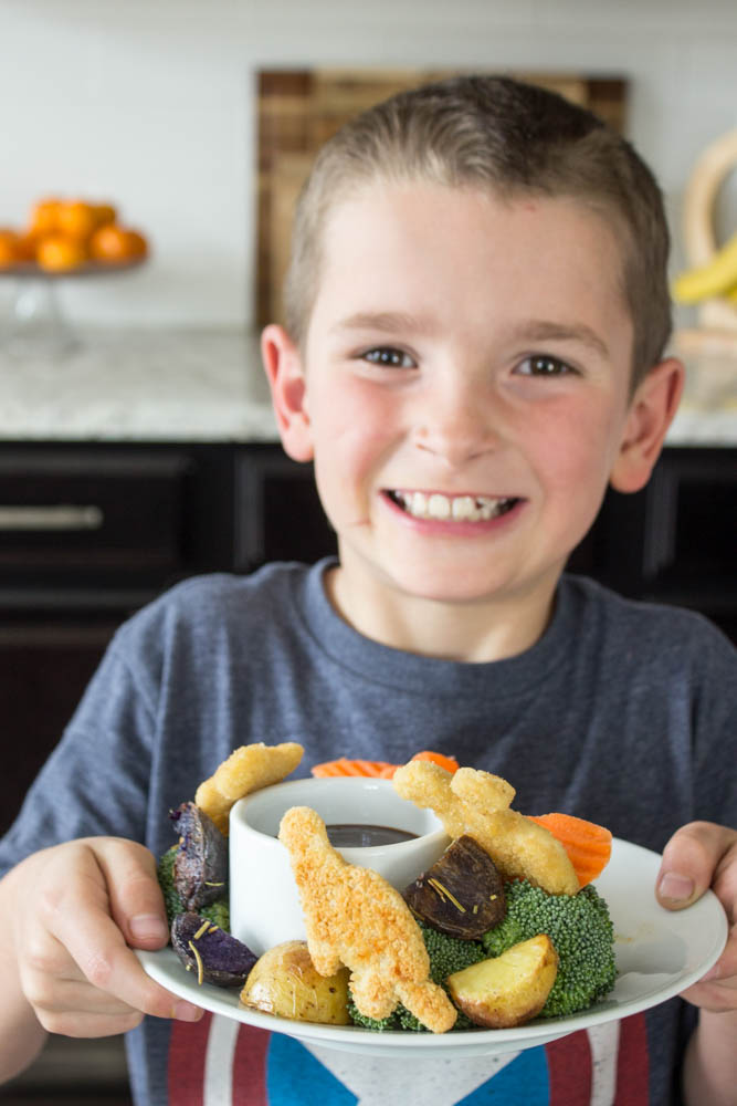 photo of a boy holding a plate of the sheet pan dinner 