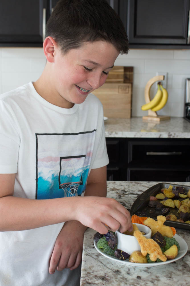 photo of an older boy dipping a dino nugget into barbecue sauce