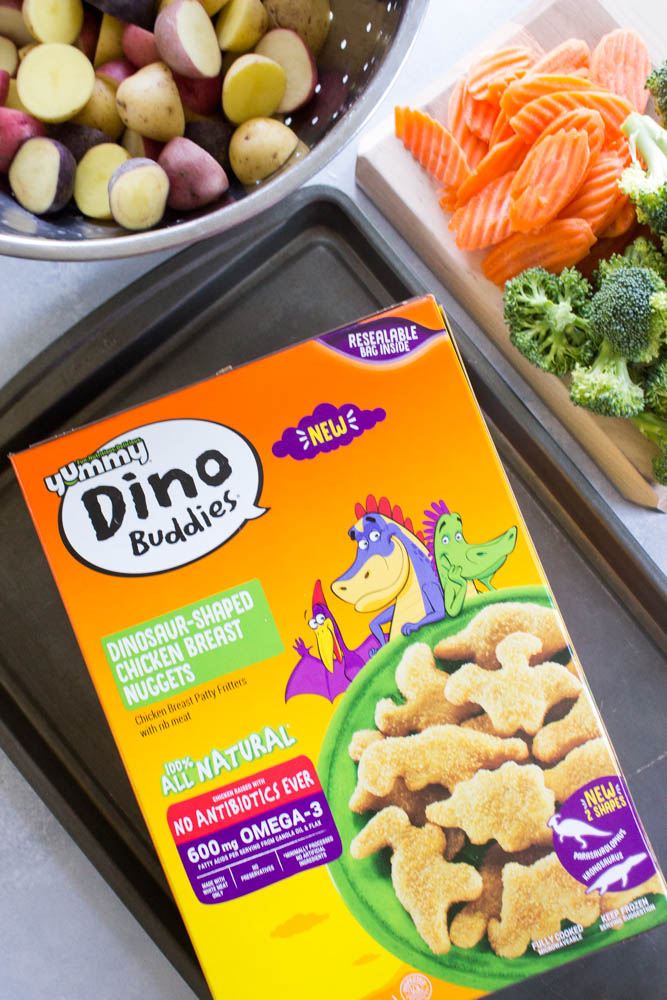 photo of a box of dino buddies nuggets on a tray with bowl of potatoes and cutting board with veggies