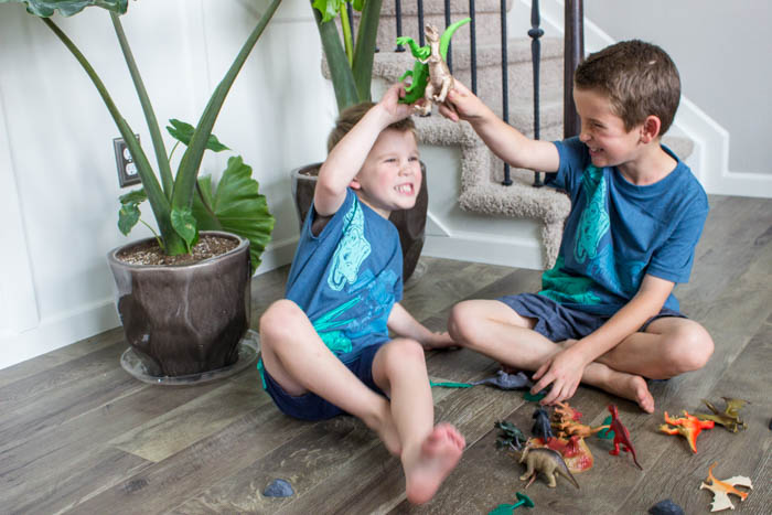 photo of 2 boys playing with plastic dinosaur toys
