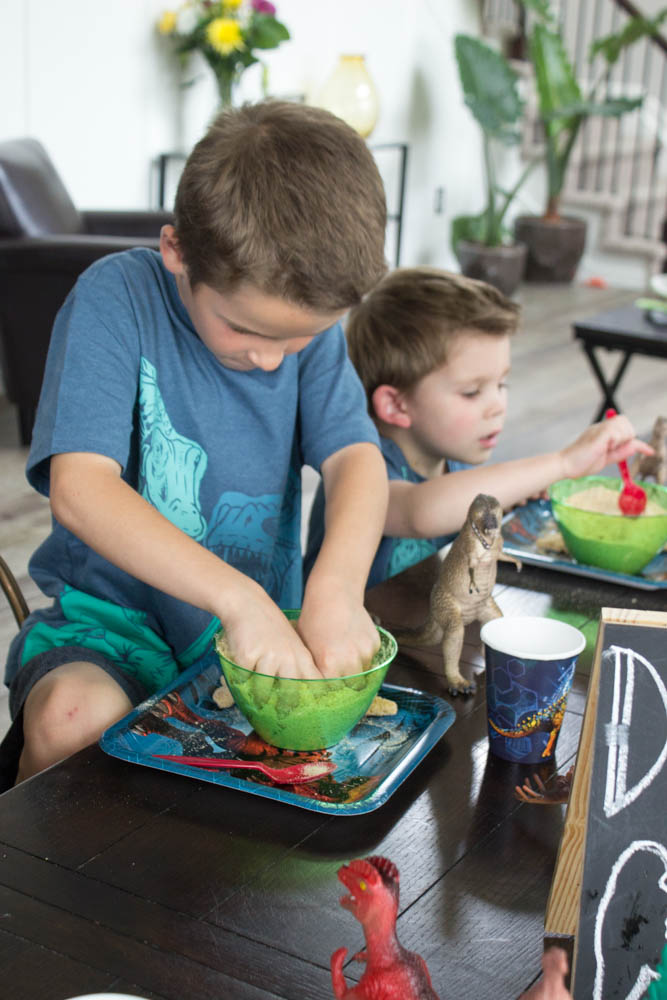 photo of 2 young boys digging for dino nuggets in green bowls
