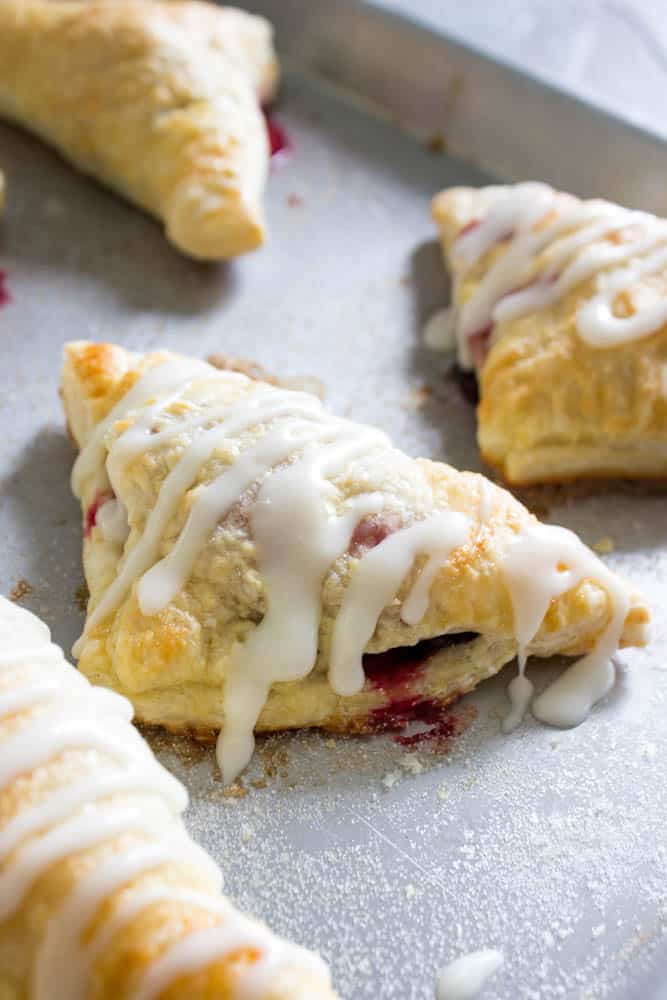 photo of Chocolate Raspberry Turnovers  on sheet pan with drizzed white icing