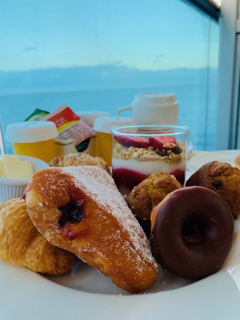 plate of breakfast pastries and parfait with ocean in background