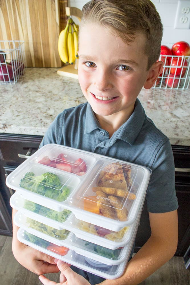 photo of a boy holding prepped lunch boxes