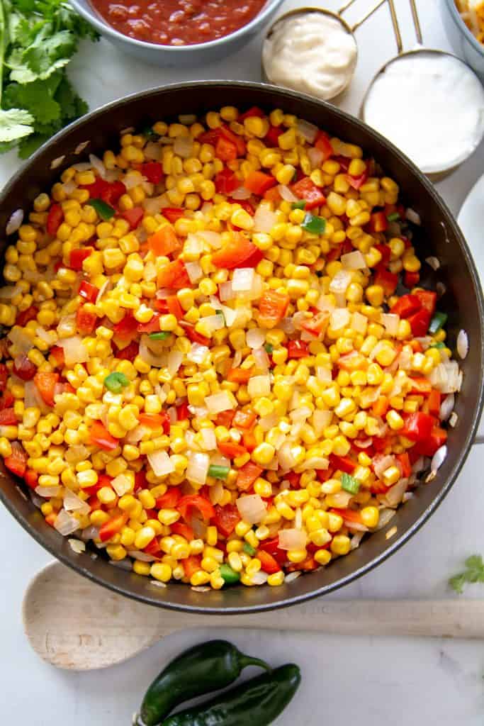 skillet filled with corn, red bell peppers, onions and jalapenos