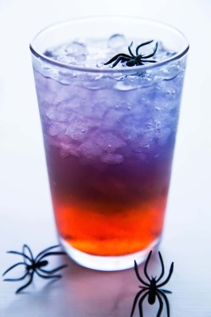 photo of a glass of spiderman punch with spider rings in and around glass