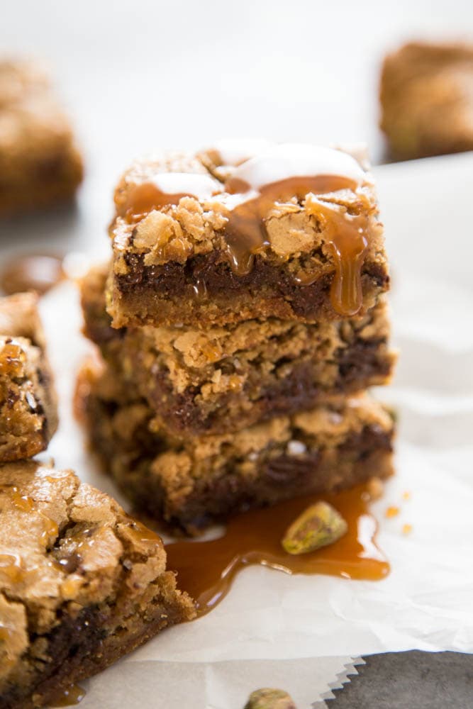 A stack of Dark Chocolate & Pistachio Cookie Bars with caramel drizzle